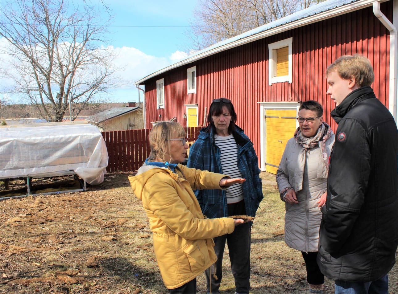 Sonja Lapveteläinen (vas.), Kirsi Mertala, Lis-Marie Enroth-Niemi ja Kim Hållfast museon sisäpihassa. Kalastajatupa tulee kiinni taustalla näkyvän punaisen liiterin päätyyn. Nyt tuvan hirret ovat suojassa pressun alla.