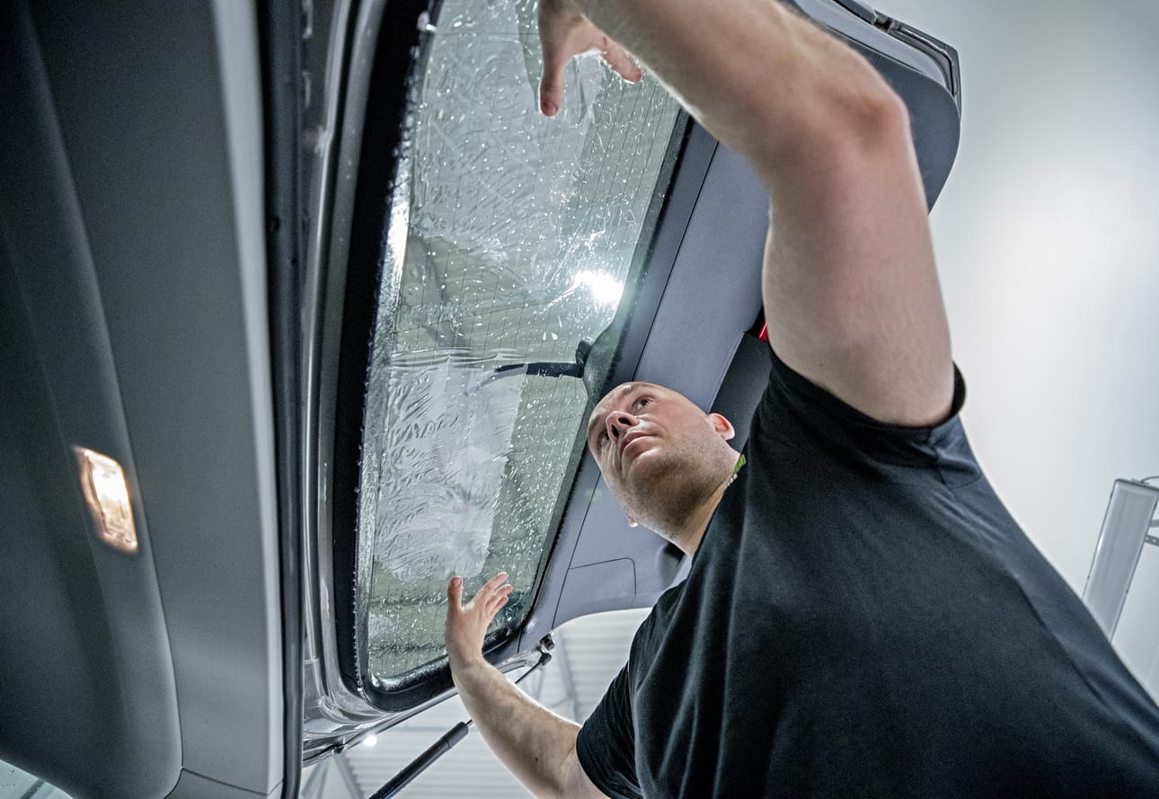 Jaakko Lappalainen asentaa tummennuskalvon märkään pintaan tarkasti paikalleen.