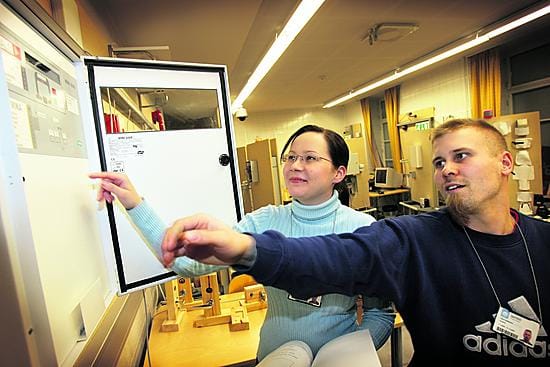Turvatekniikanlaboratoriossa. Torstaina turvallisuusvalvojiksi valmistuvat Jenni Lämsä ja Ismo Kukkohovi tarkastamassa paloilmoitinkeskusta.
